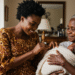 Nigerian mum watching her baby being held by grandmother with a loving smile__davinciblog_ng